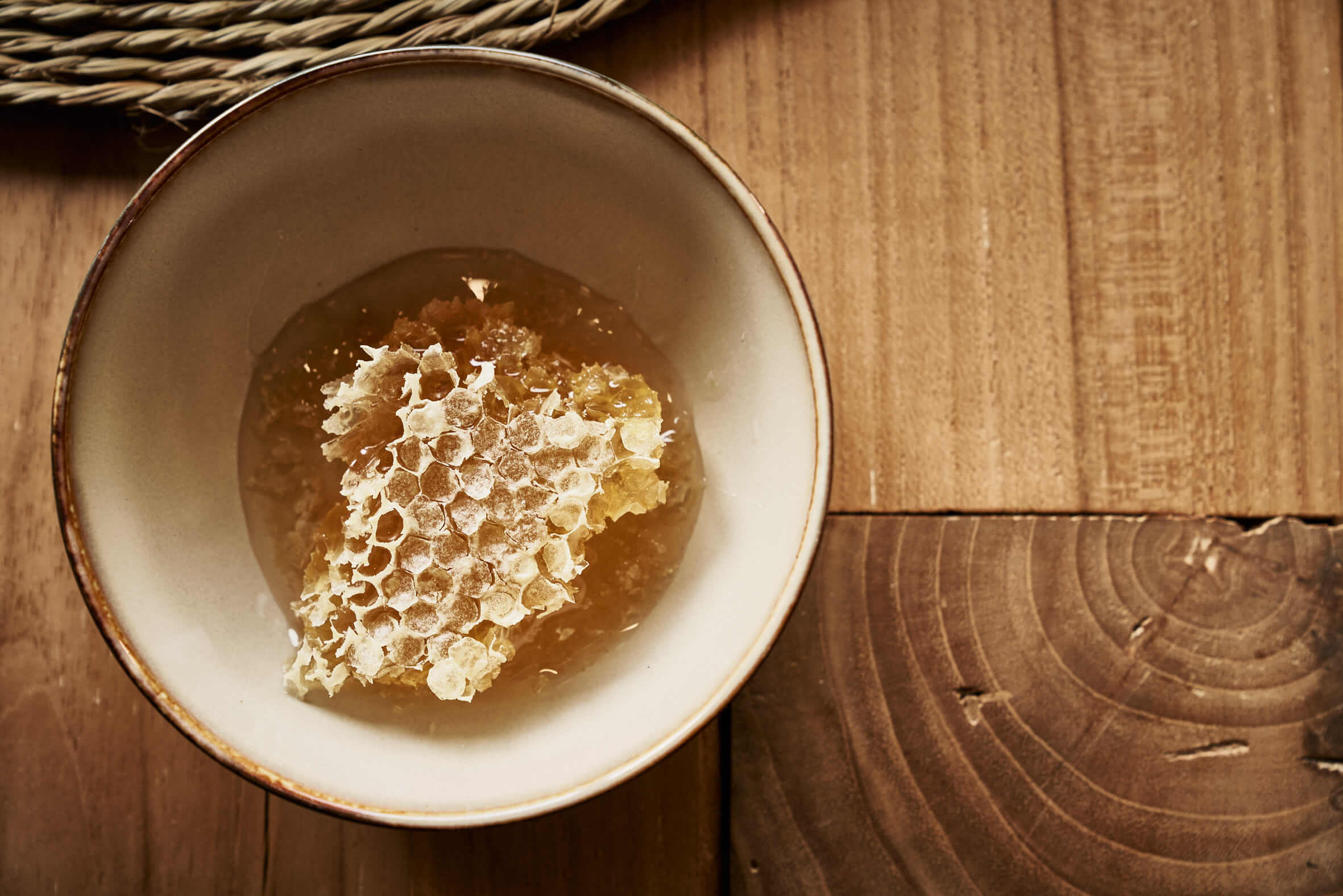 Piece of honeycomb in a bowl on a wooden table