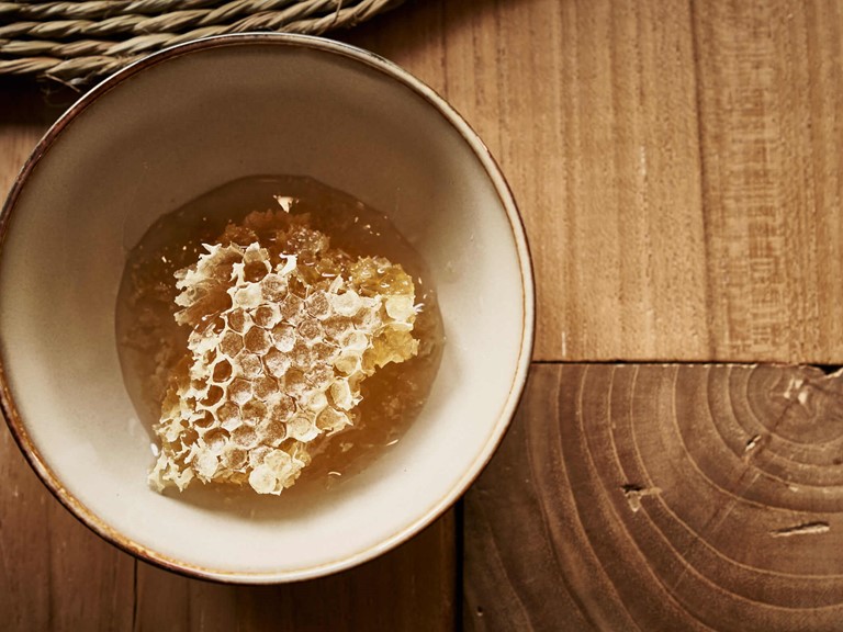 Piece of honeycomb in a bowl on a wooden table