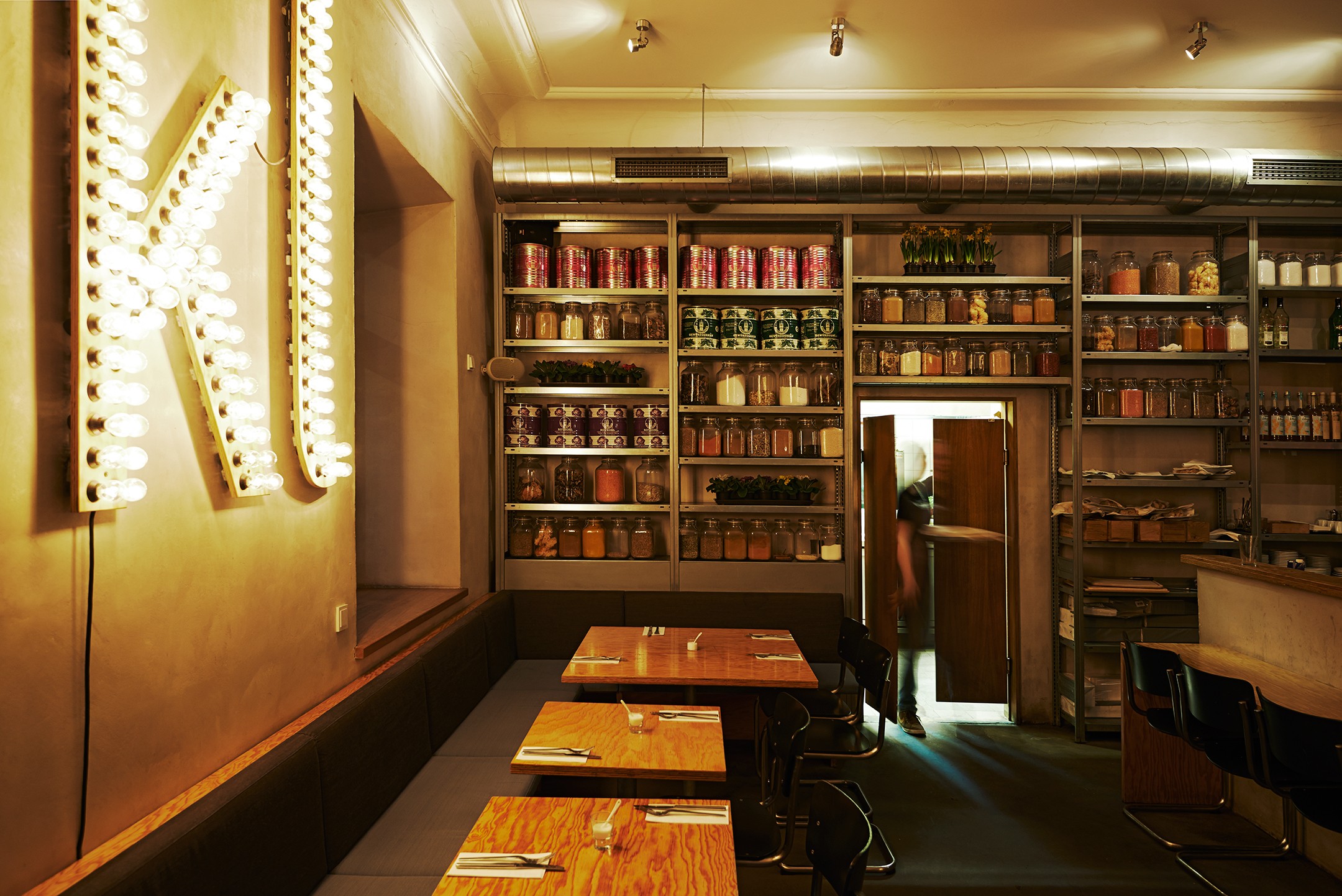 Eine gemütliche Ecke in einem Restaurant. An der Wand sind Regalwände mit verschiedenen Zutaten. 