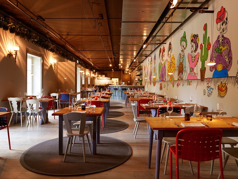 Ein Restaurant mit bunten Möbeln und Tapeten, das die Vielfalt Lateinamerikas verkörpert.