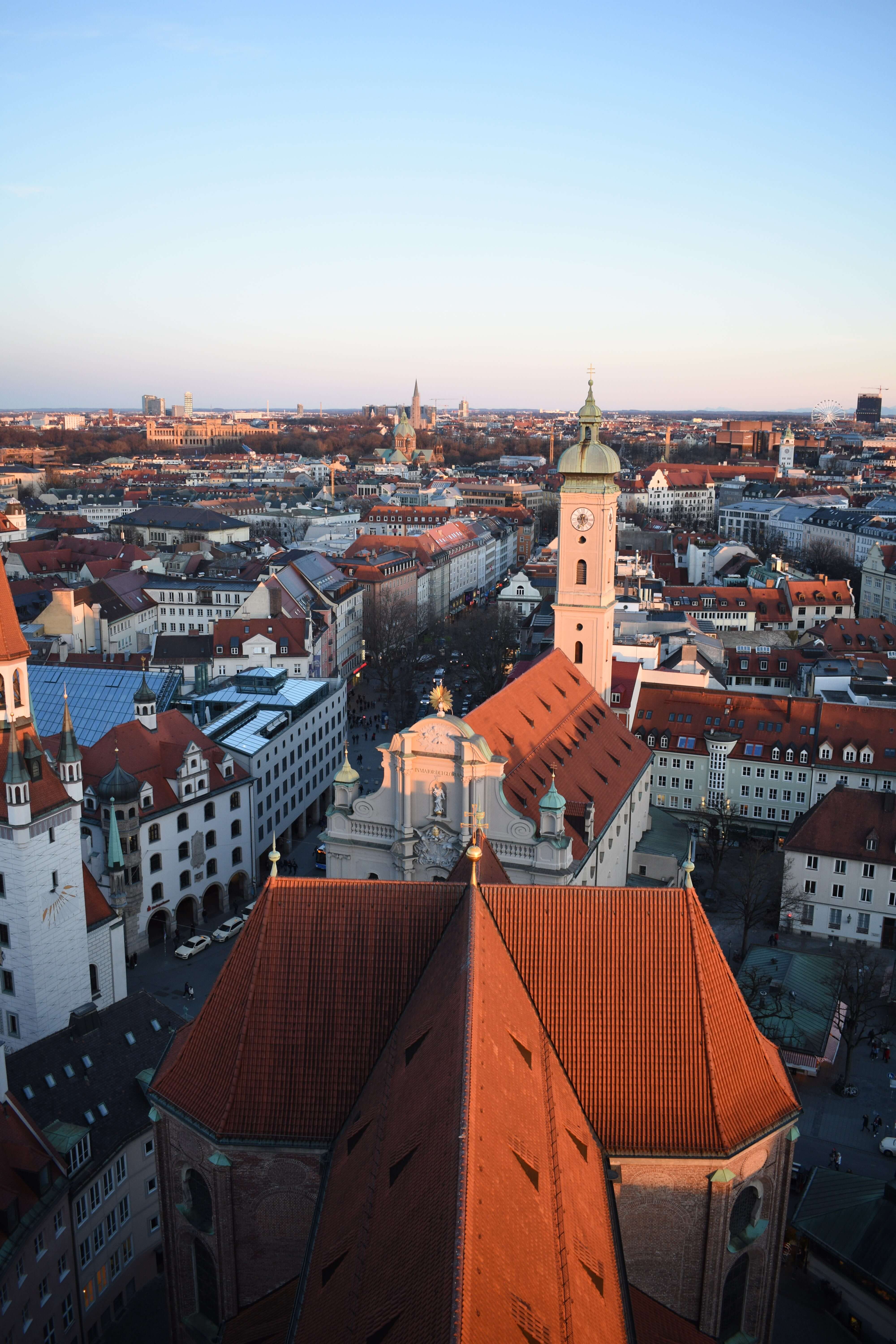 View over the roofs of a city with many historic buildings, the red-tiled roof of the transept of a church in the middle
