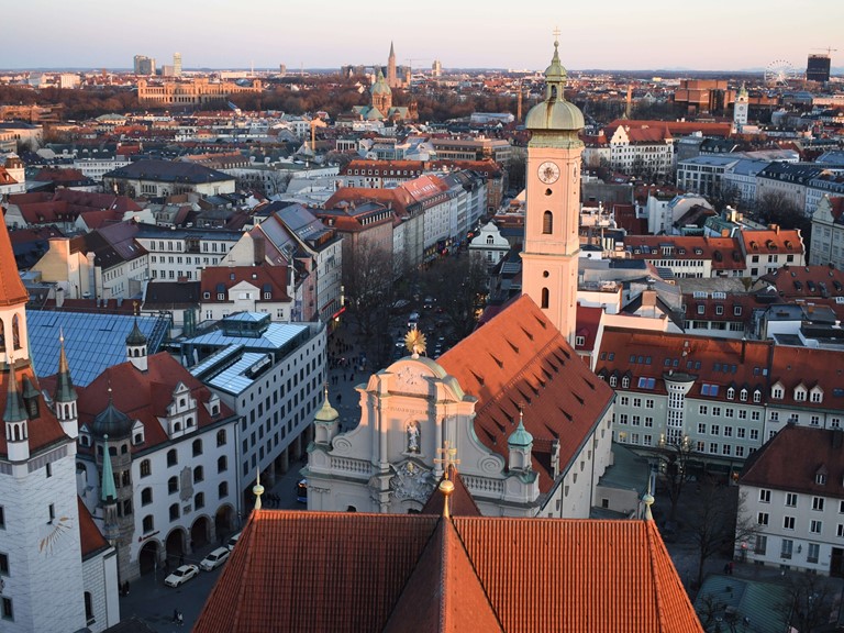View over the roofs of a city with many historic buildings, the red-tiled roof of the transept of a church in the middle