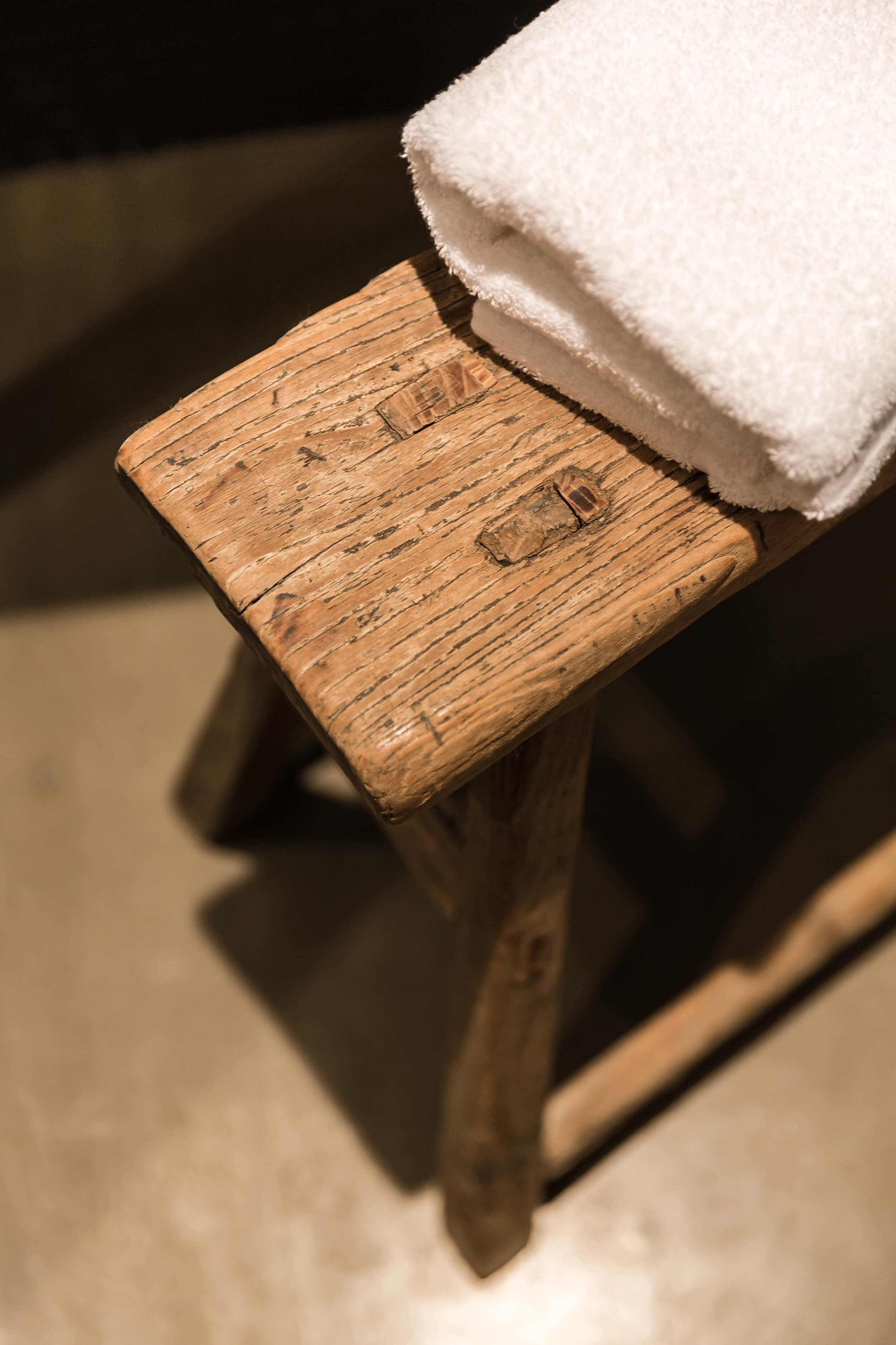 Detail of a wooden stool with a white towel. 