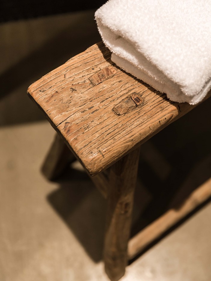 Detail of a wooden stool with a white towel. 