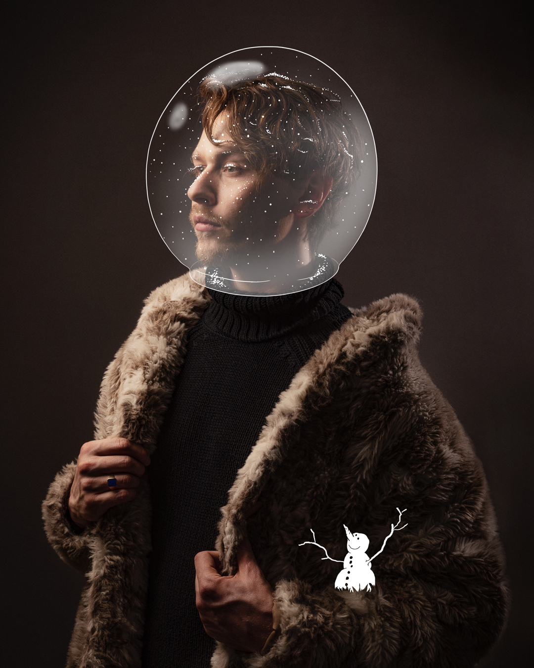 Stehender Mann mit rotem Haar und Bart in Rollkragenpullover und Mantel aus Kunstpelz, er trägt eine illustrierte Schneekugel auf dem Kopf, ein Schneemann sitzt in seiner Armbeuge