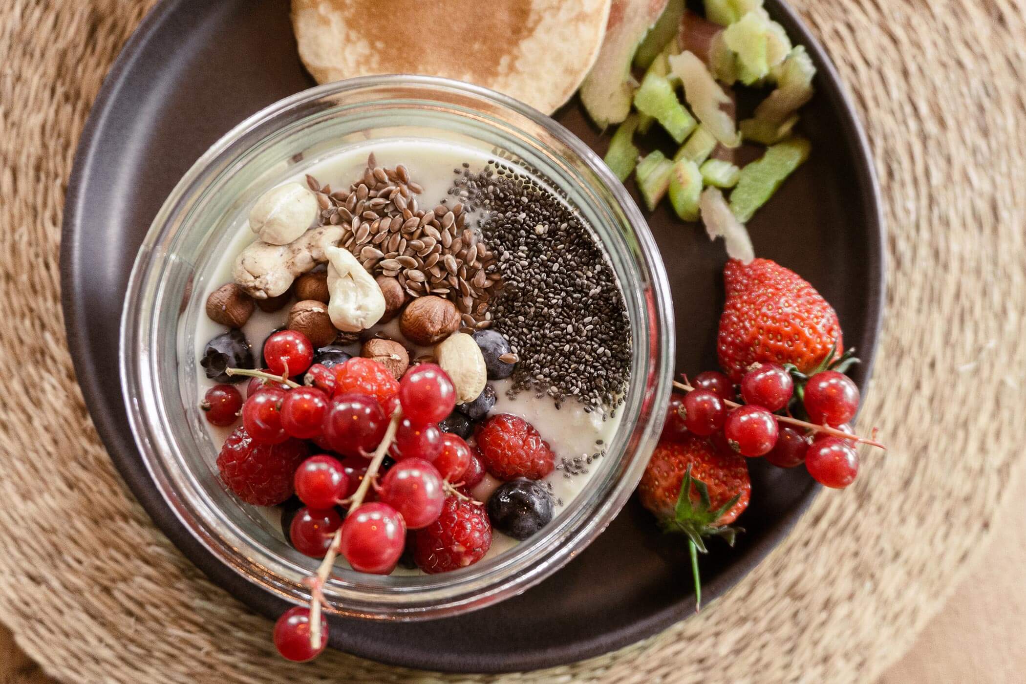 A breakfast plate with yoghurt and various toppings, berries and pancakes