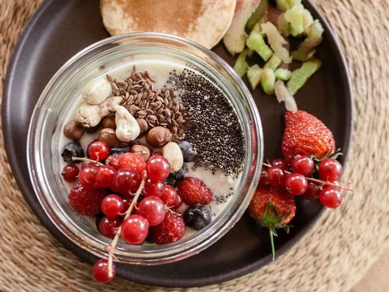Ein Frühstücksteller mit Joghurt und verschiedenen Toppings, Beeren und Pancakes
