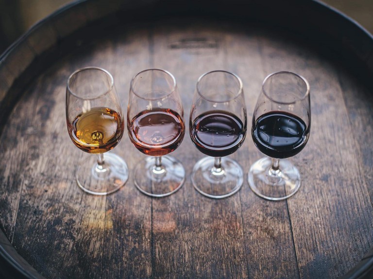 Weingläser mit verschiedenen Weinen stehen auf einem Holzfass