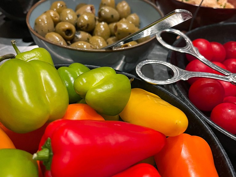 Paprika, Tomaten, Oliven und Aufstriche in Schalen am Buffet.