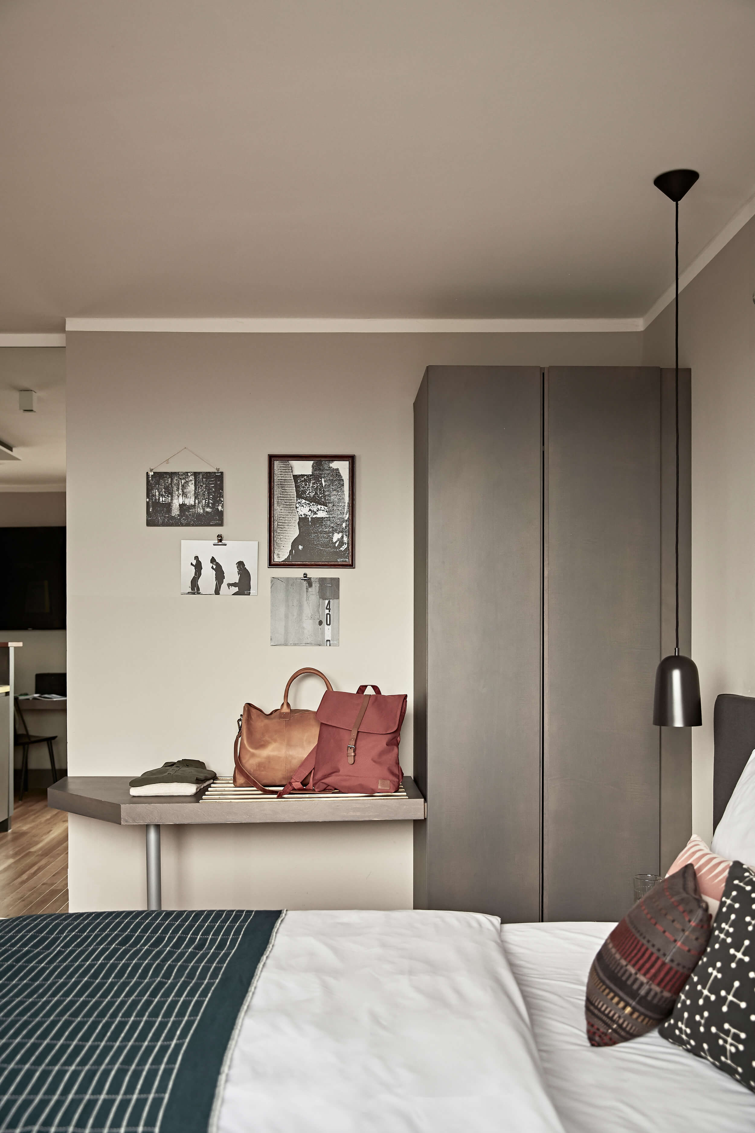 Cosy double bed with accessories, a grey wardrobe, a shelf with pockets and modern pictures on the wall.