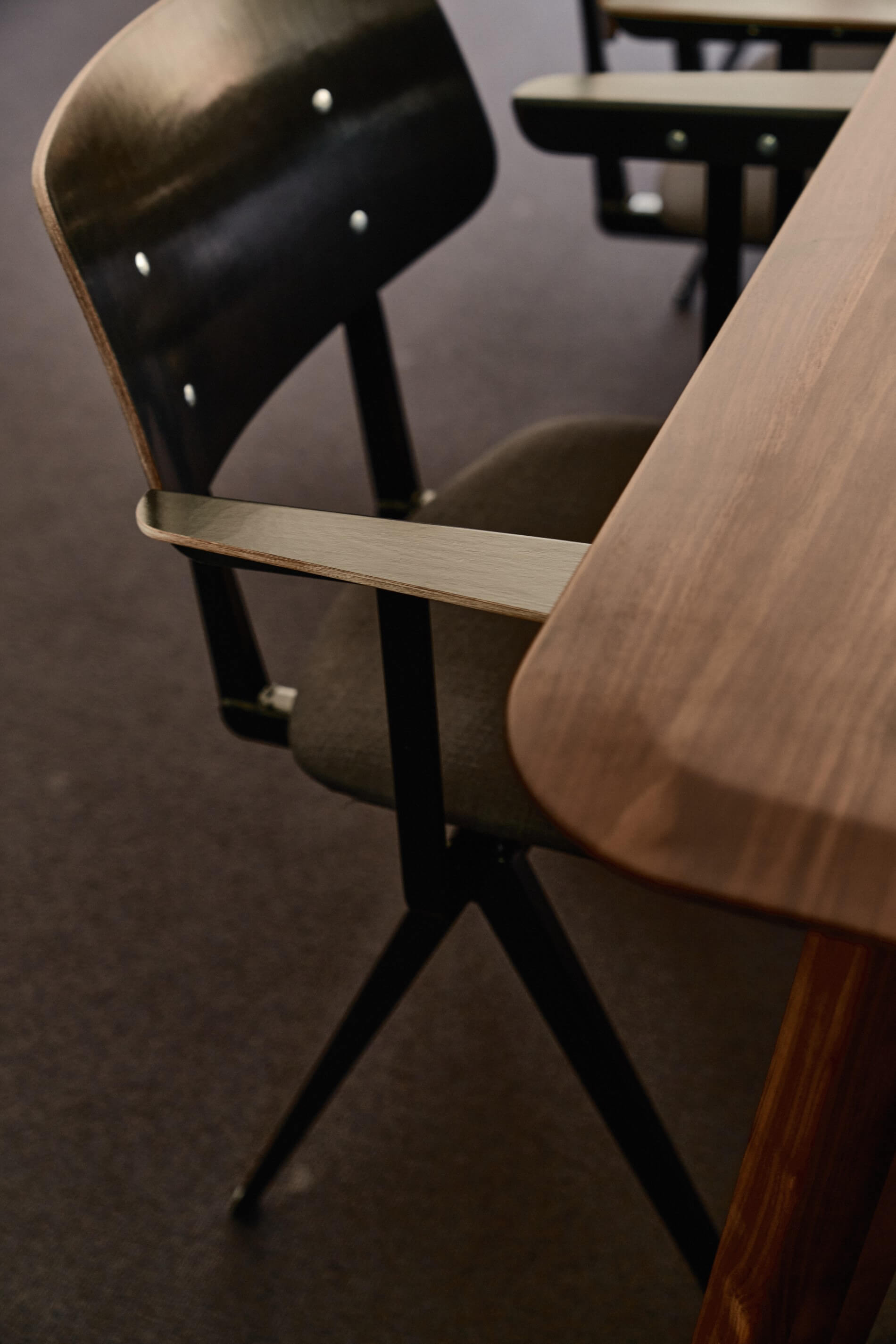 A close-up of a wooden chair in a meeting room.