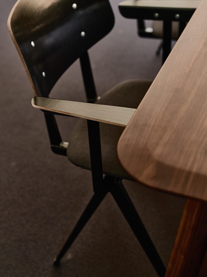 A close-up of a wooden chair in a meeting room.