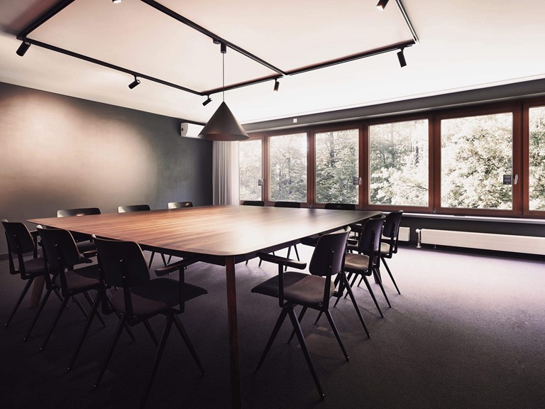 A conference room with large windows with a direct view of the green surroundings.