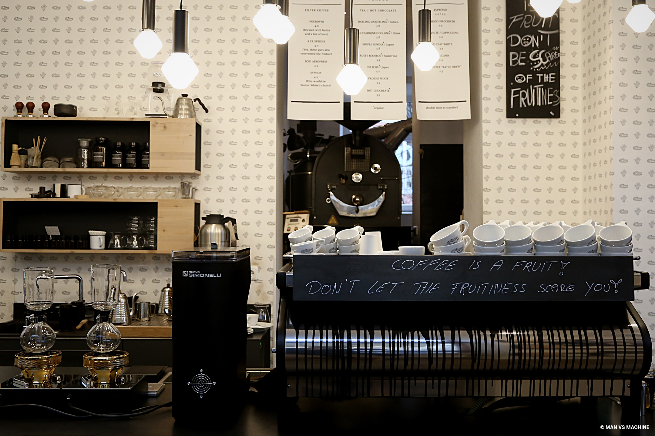 Bar eines Kaffees mit modernen Deckenleuchten, einer großen Kaffeemaschine und allem, was zur Kaffeezubereitung nötig ist