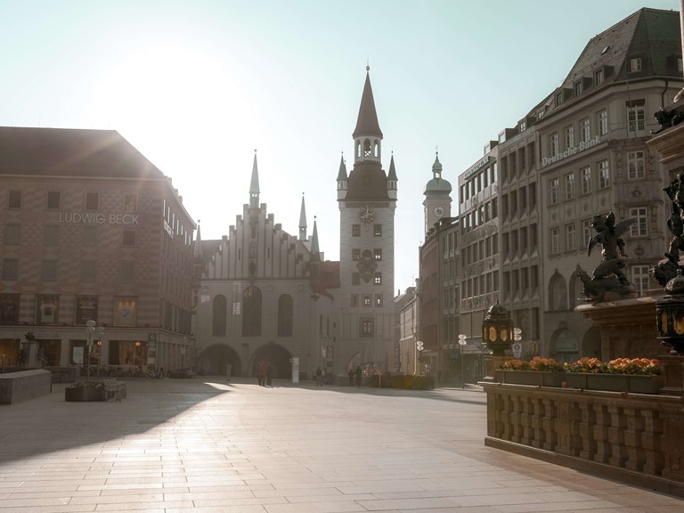 A square in soft morning light, all around are historic buildings and department stores