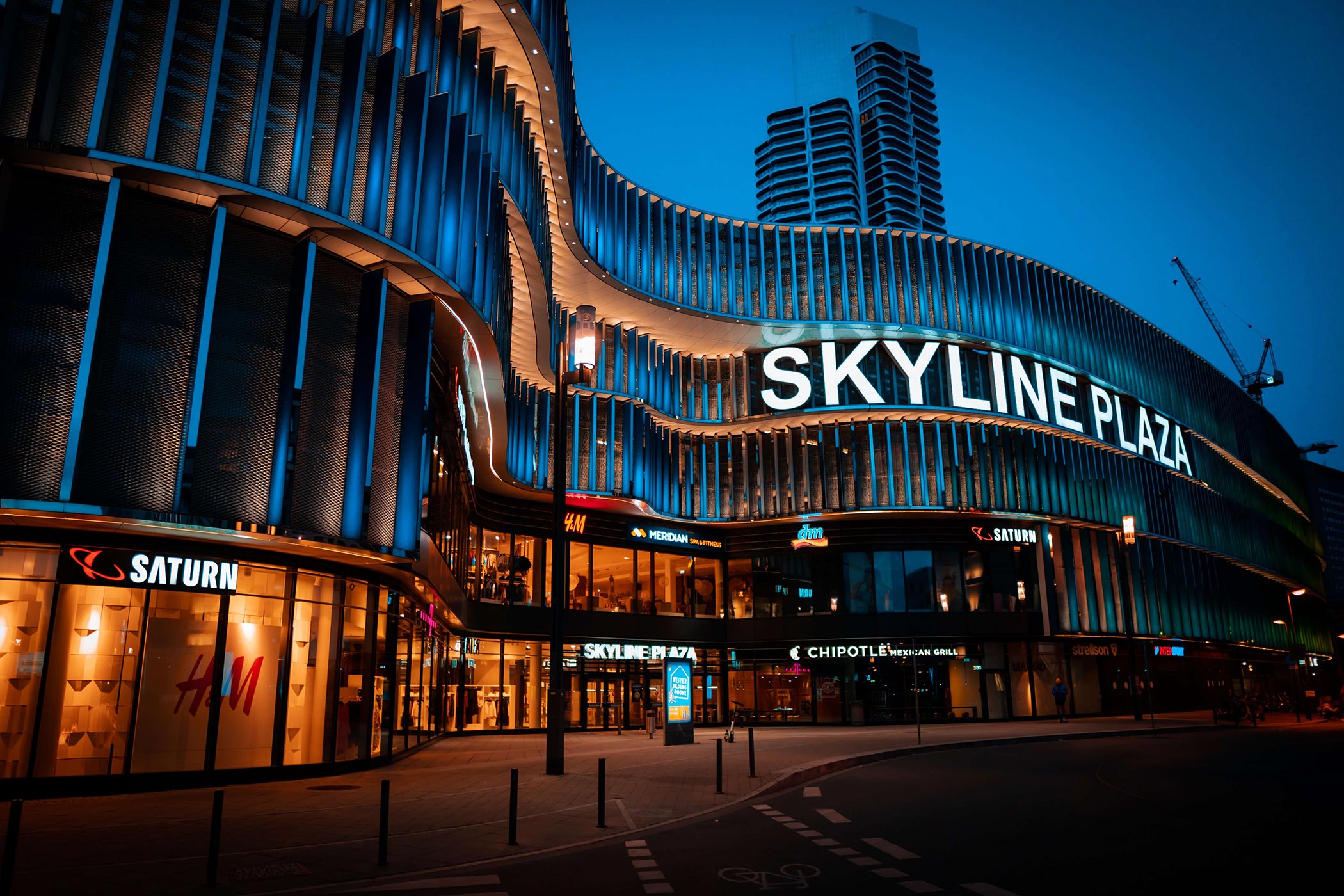 Futuristic looking shopping mall with names of the shops and a big lettering saying "Skyline Plaza"