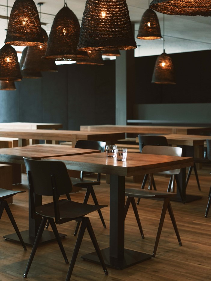 Das Bold-Restaurant mit Holzboden und -tischen sowie schwarzen Stühlen und Designerleuchten