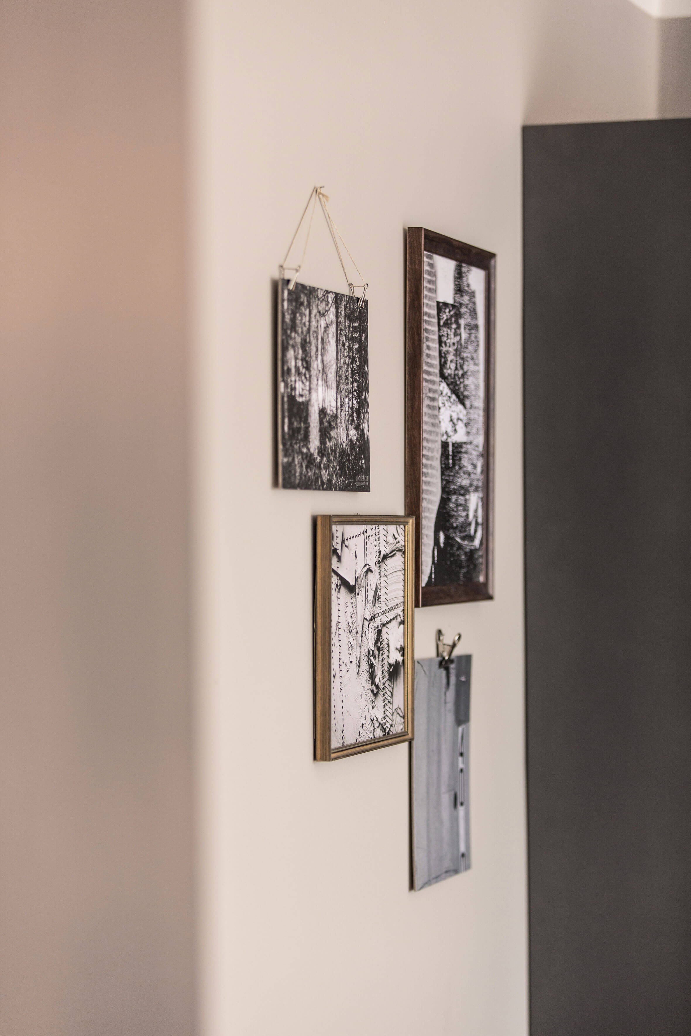 Pictures in black and white, with and without frames, hanging on the wall next to a dark grey cupboard. 